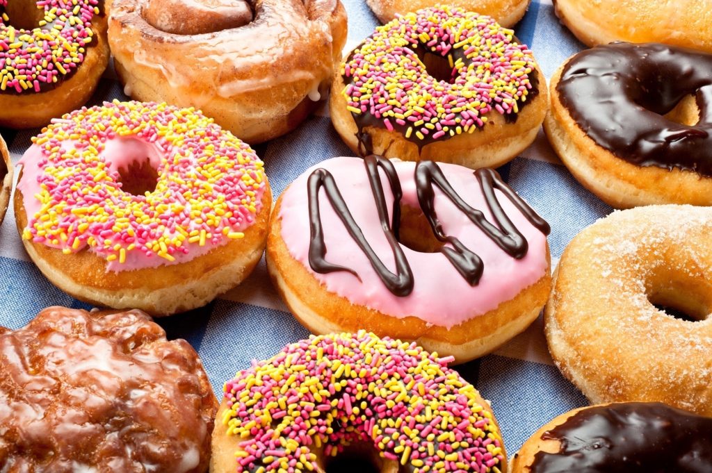 Close up of a selection of colorful donuts. Focus is on middle row.