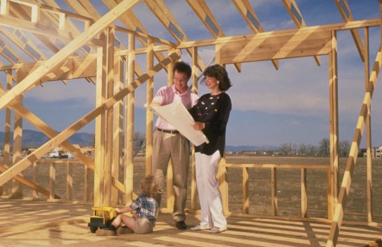 man and woman standing in unfininshed home looking at blueprints