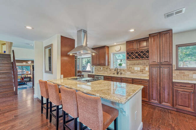 open floor plan kitchen with stainless range hood and seating at center island