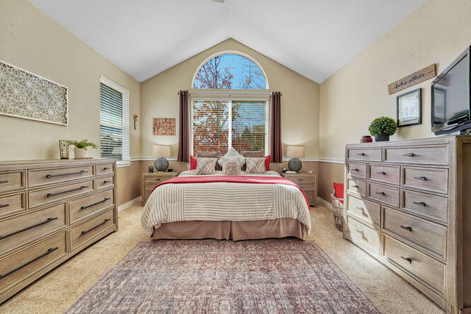 ensuite private primary bedroom with vaulted ceiling and neutral color tones