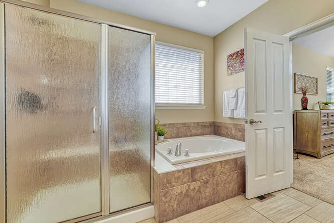 large soaking tub and shower with seeded glass shower