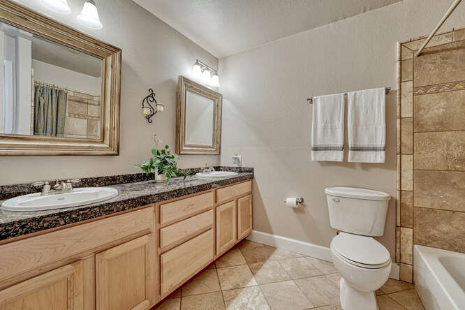 bathroom with double sinks and custom tile shower
