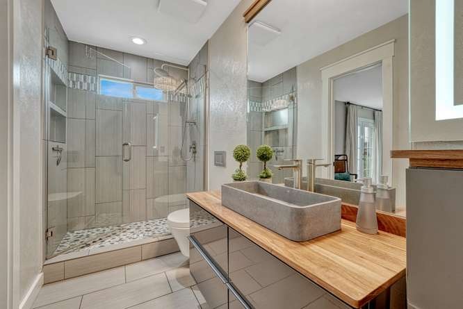 renovated bath with walkin shower, pebble base, frameless glass surround and raised sink
